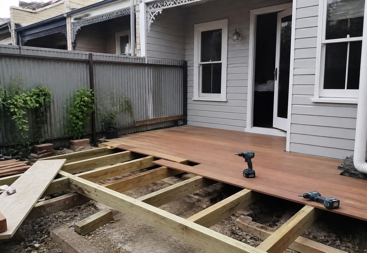 A finished spotted gum deck in a Northcote backyard, boards laid level with the back door threshold.